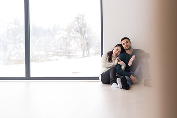 Image showing multiethnic couple sitting on the floor near window at home