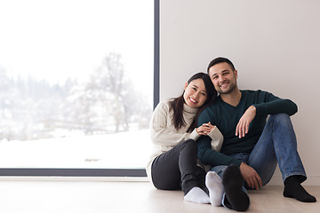 Image showing multiethnic couple sitting on the floor near window at home