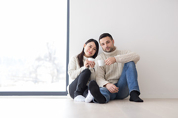 Image showing multiethnic couple enjoying morning coffee by the window