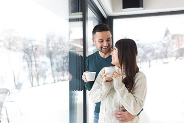 Image showing multiethnic couple enjoying morning coffee by the window