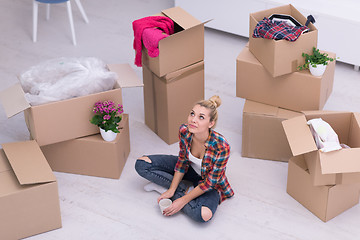 Image showing woman with many cardboard boxes sitting on floor