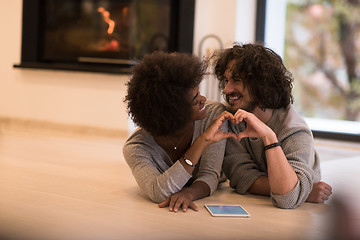 Image showing multiethnic couple showing a heart with their hands on the floor