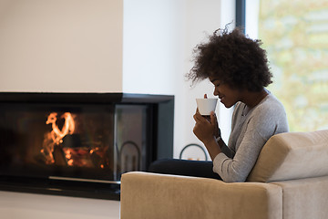 Image showing black woman drinking coffee in front of fireplace