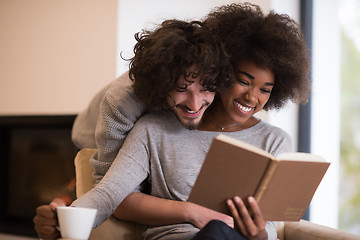 Image showing multiethnic couple hugging in front of fireplace