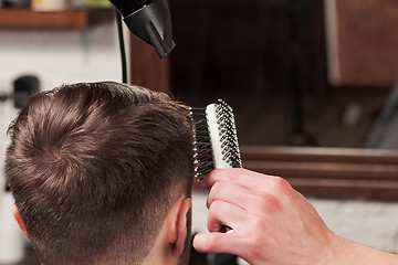 Image showing The hands of barber making haircut to young man in barbershop