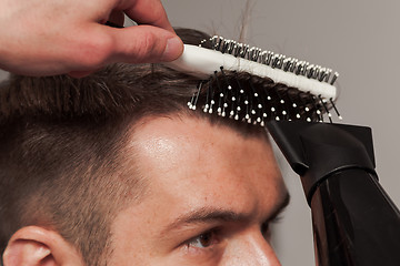 Image showing The hands of barber making haircut to young man in barbershop