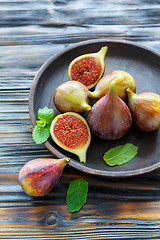 Image showing Ripe figs and mint leaves on a wooden dish.