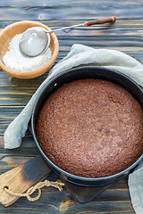 Image showing Chocolate cake in a metal form and bowl with powdered sugar.