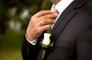 Image showing The groom in a suit, corrects a tie with his hand.