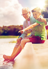 Image showing grandfather and grandson sitting on river berth