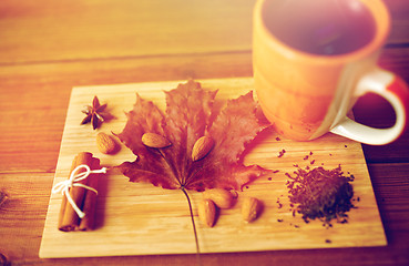 Image showing cup of tea, maple leaf and almond on wooden board