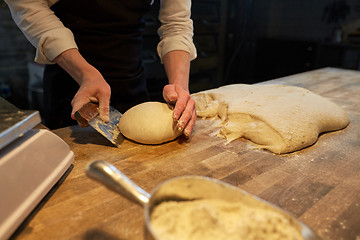 Image showing baker portioning dough with bench cutter at bakery