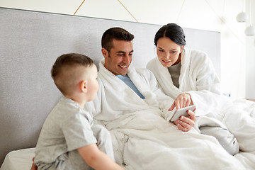 Image showing happy family with smartphone in bed at hotel room