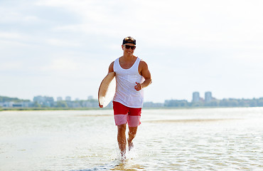 Image showing happy young man with skimboard on summer beach