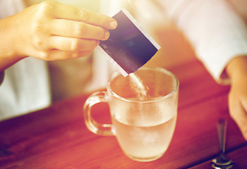 Image showing woman pouring medication into cup of water