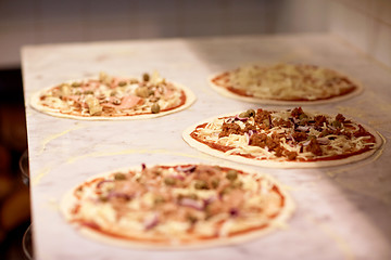 Image showing raw pizza with grated cheese on table at pizzeria