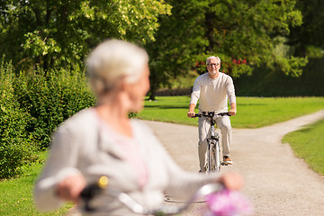 Image showing happy senior couple riding bicycles at summer park