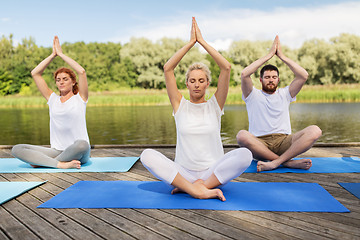 Image showing people meditating in yoga lotus pose outdoors