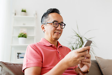 Image showing asian man with smartphone sitting on sofa at home
