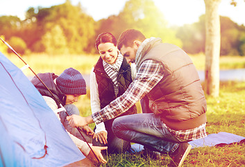 Image showing happy family setting up tent outdoors