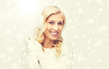 Image showing smiling young woman in winter earmuffs and sweater