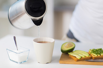 Image showing kettle pouring hot water to tea cup at home