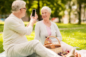 Image showing senior couple taking picture by smartphone at park