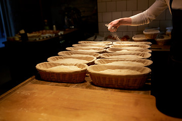 Image showing baker with baskets for dough rising at bakery