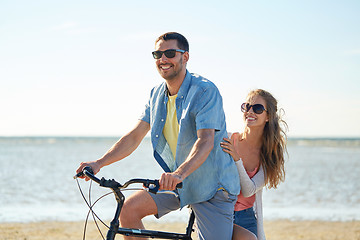 Image showing happy young couple riding bicycle on beach