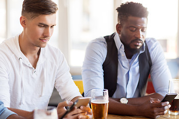 Image showing male friends with smartphone drinking beer at bar