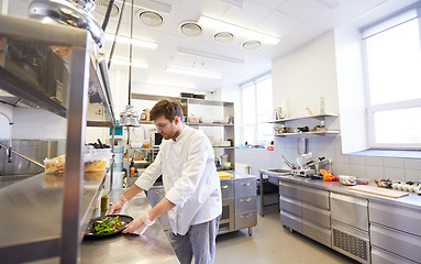 Image showing happy male chef cooking food at restaurant kitchen