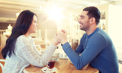 Image showing happy couple with tea holding hands at restaurant