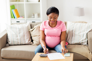 Image showing pregnant woman with bills and money at home