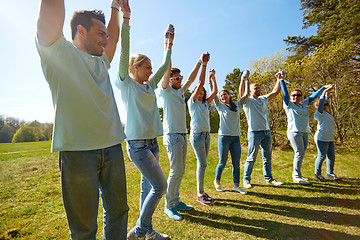 Image showing group of happy volunteers holding hands outdoors