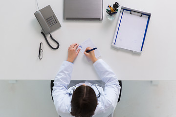 Image showing doctor writing prescription at table