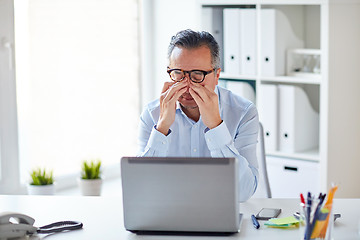 Image showing tired businessman in glasses with laptop at office