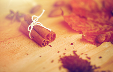 Image showing cinnamon, maple leaf and almond on wooden board