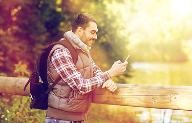 Image showing happy man with backpack and smartphone outdoors