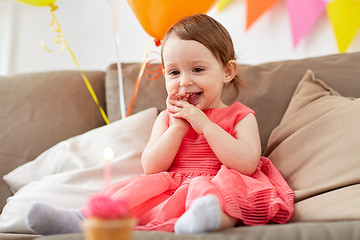 Image showing happy baby girl looking at birthday cupcake