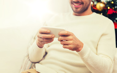 Image showing smiling man with smartphone at home for christmas