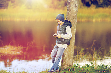 Image showing happy boy playing game on smartphone outdoors