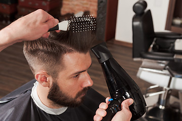 Image showing The hands of barber making haircut to young man in barbershop