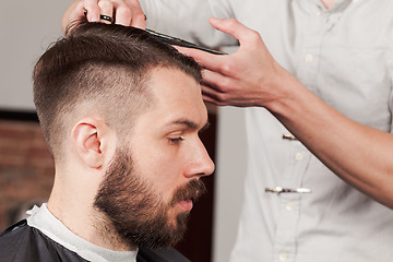 Image showing The hands of barber making haircut to young man in barbershop