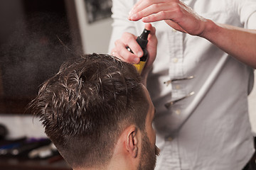 Image showing The hands of barber making haircut to young man in barbershop