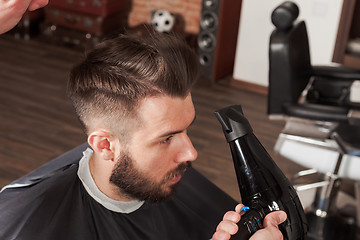 Image showing The hands of barber making haircut to young man in barbershop