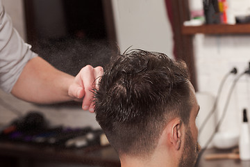 Image showing The hands of barber making haircut to young man in barbershop