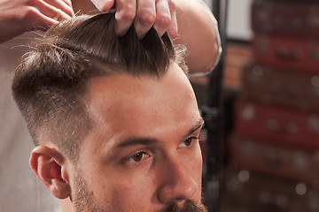 Image showing The hands of barber making haircut to young man in barbershop