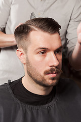 Image showing The hands of barber making haircut to young man in barbershop