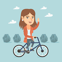 Image showing Young caucasian woman riding bicycle in the park.