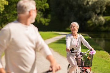 Image showing happy senior couple riding bicycles at summer park